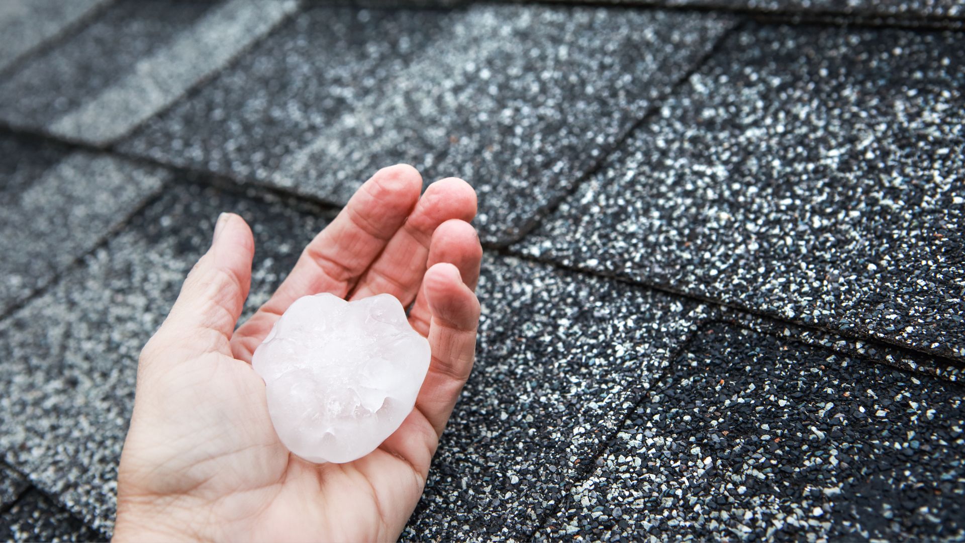 A hand holding a piece of ice on top of a roof